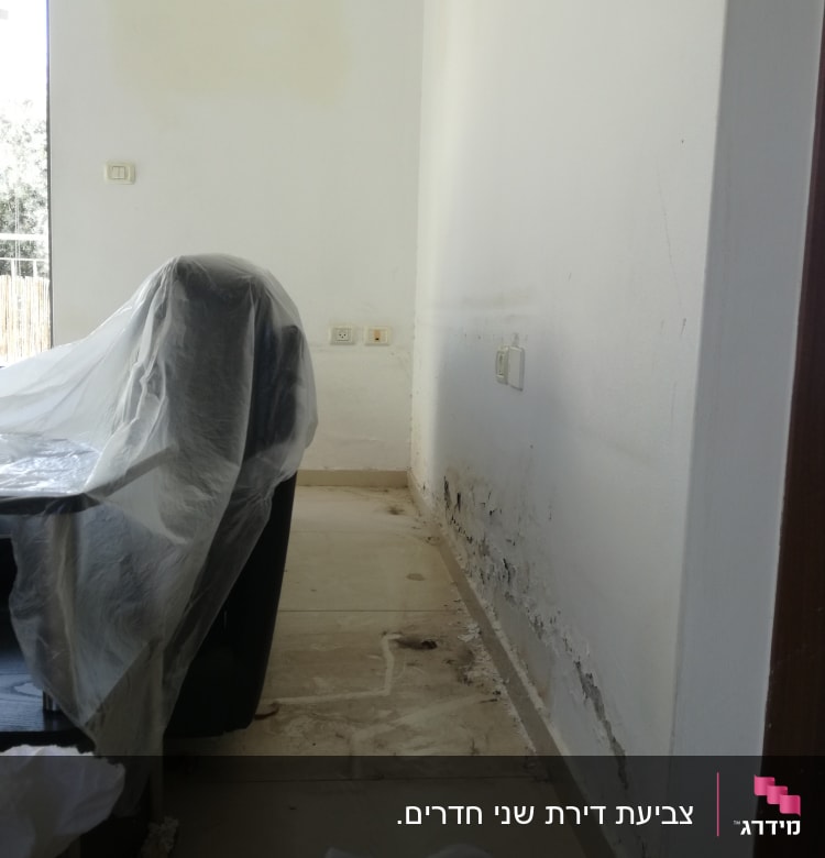 קיר עם סימני רטיבות וציוד מכוסה בניילון